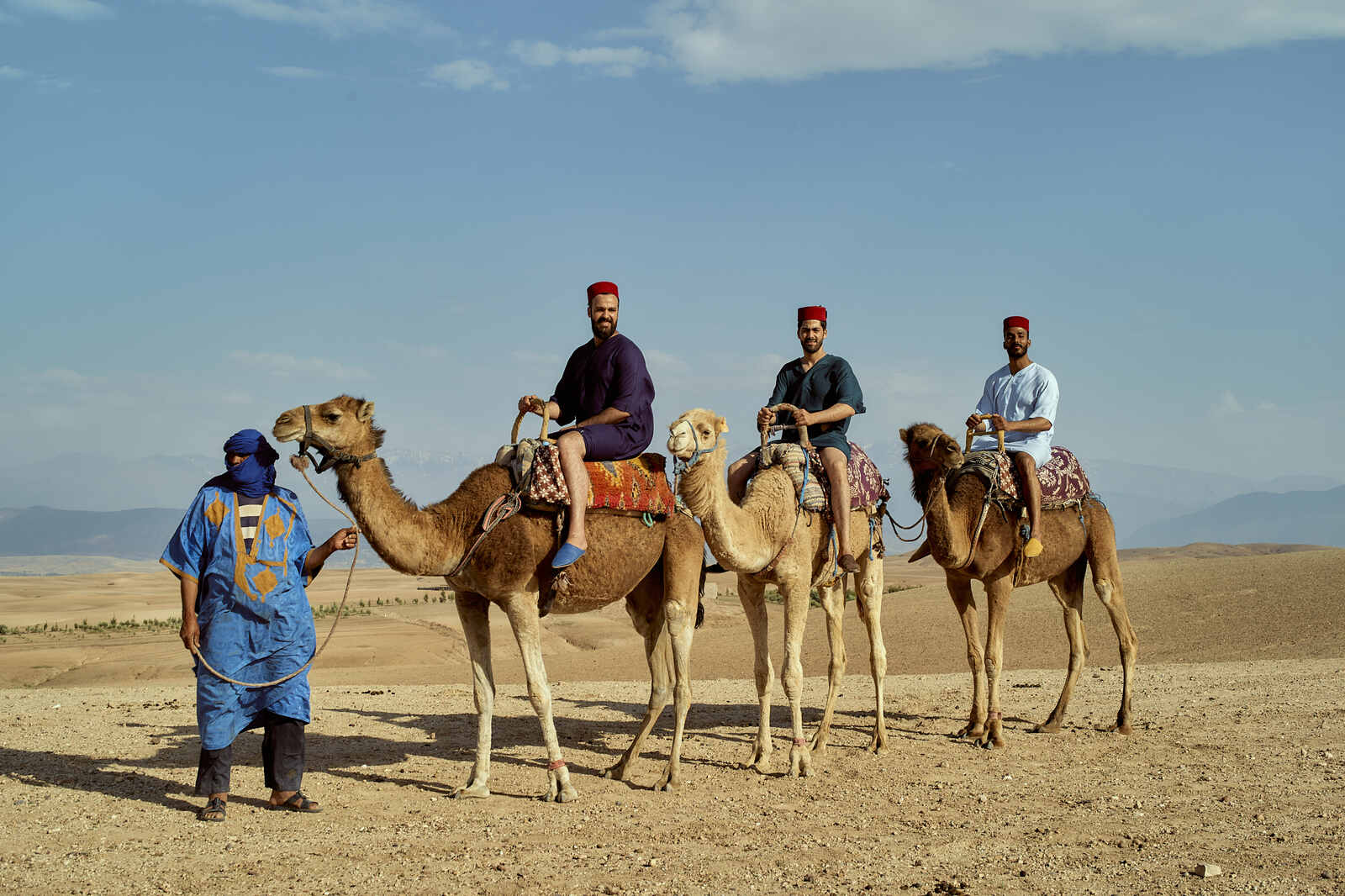 Camel ride in Agafay Desert near Marrakech at sunset with tourists enjoying the scenic view