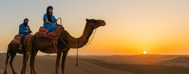 Couple riding camels in the Agafay Desert at sunset