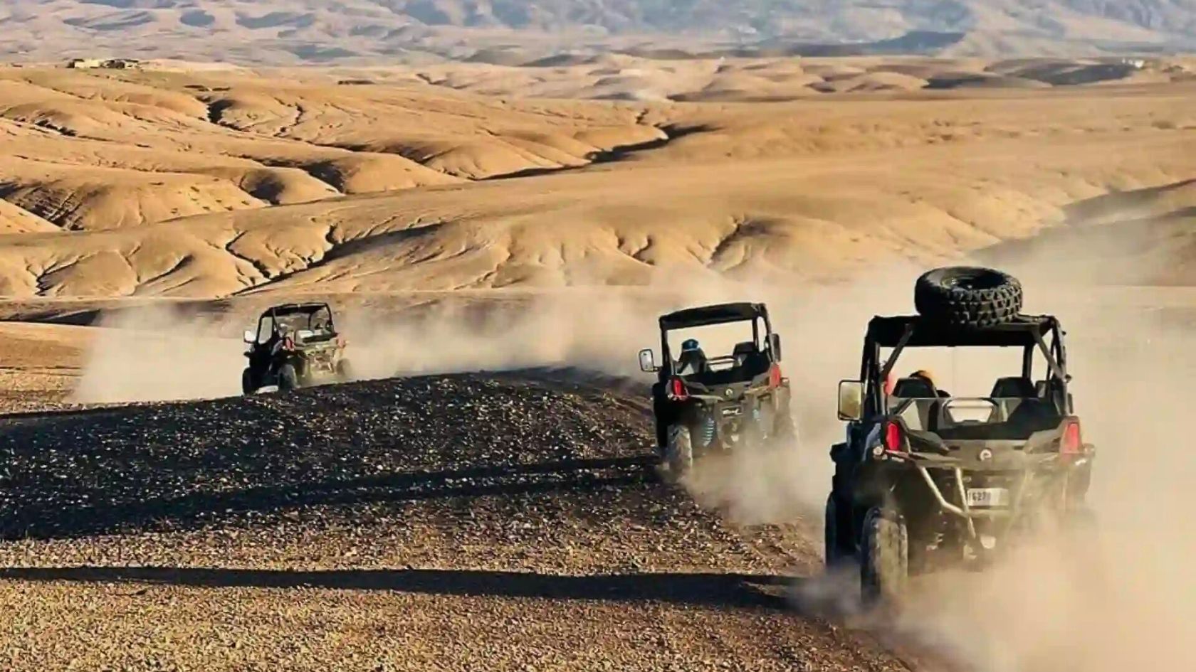 Traveler driving a buggy across the Agafay Desert with a scenic view of Morocco’s golden hills near Marrakech.