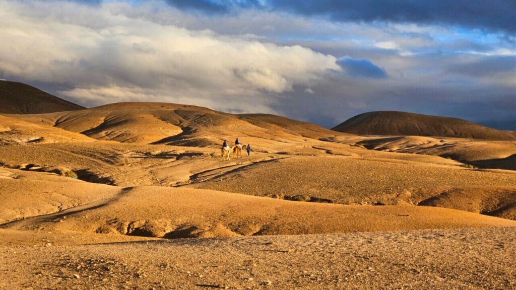 Traveler riding a camel through the Agafay Desert near Marrakech, Morocco.