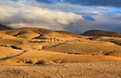 Agafay Desert day trip: Traveler riding a camel through the Agafay Desert near Marrakech, Morocco.
