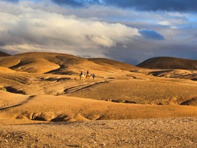 Agafay Desert day trip: Traveler riding a camel through the Agafay Desert near Marrakech, Morocco.